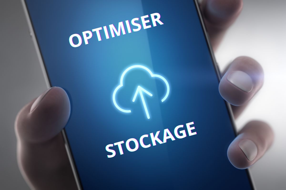 Main tenant un smartphone affichant le texte "OPTIMISER STOCKAGE" avec une icône de nuage sur l'écran.